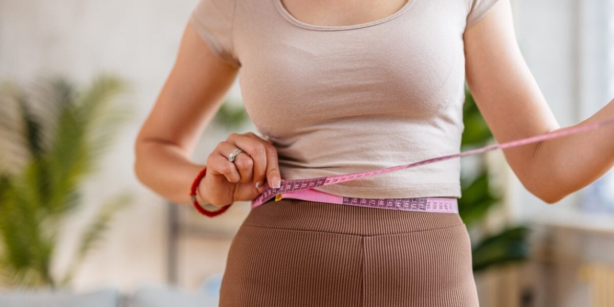 Young Woman Measuring Her Waist at home Young Woman Measuring Her Waist at home